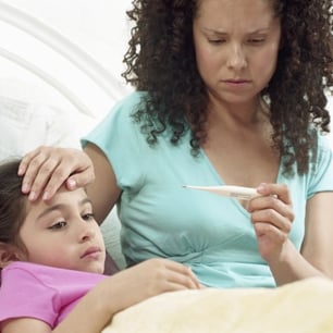 mother looking at sick daughters thermometer