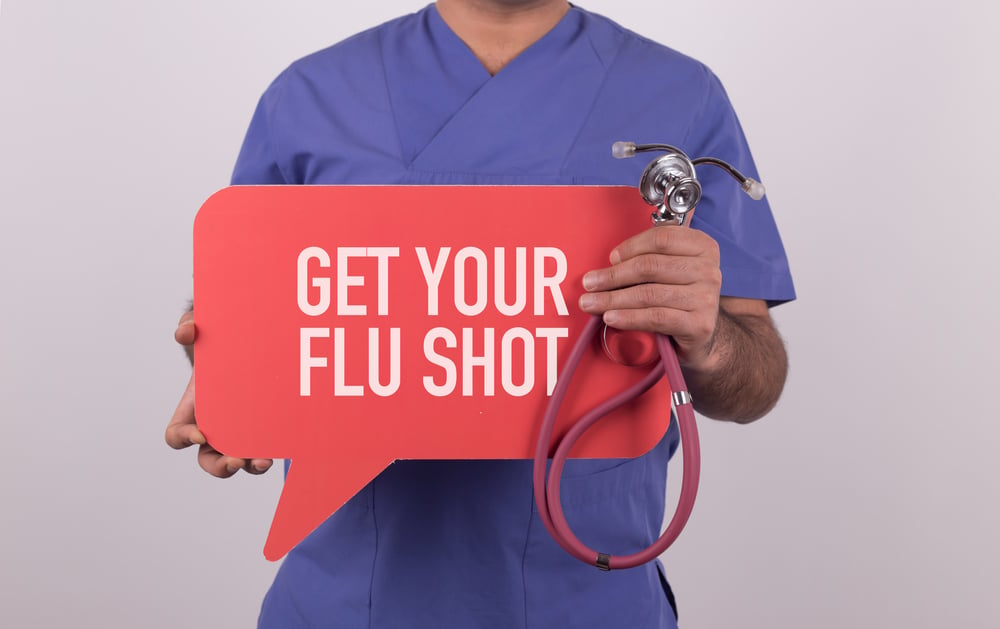 doctor holding get your flu shot sign