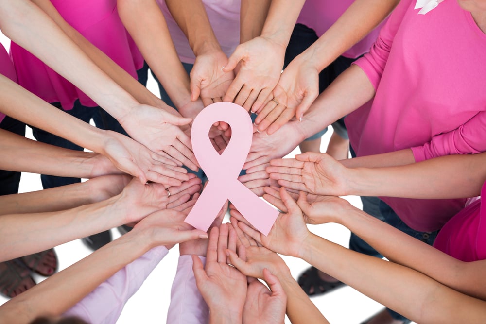hands joined in a circle holding breast cancer symbol